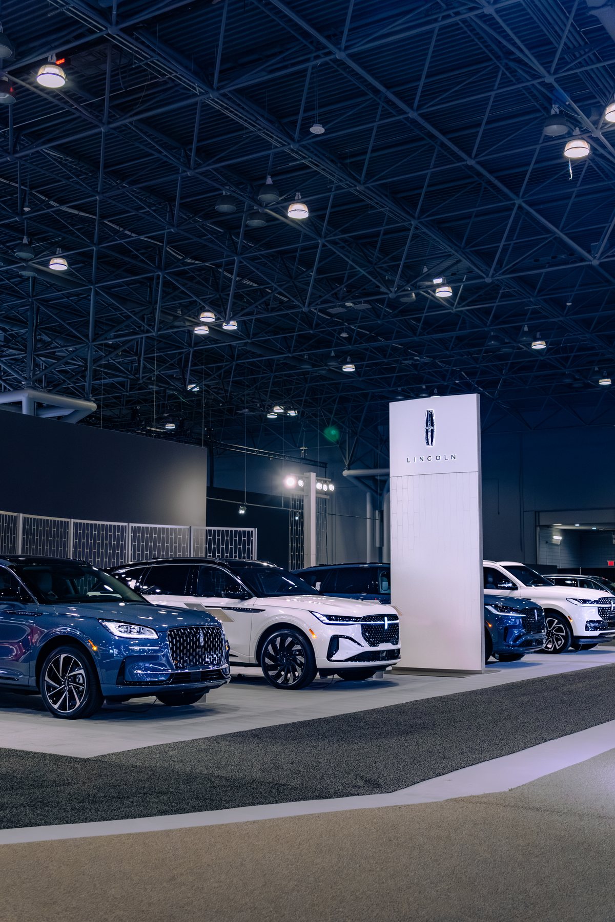 A lineup of Lincoln SUVs on display inside an auto show exhibition hall