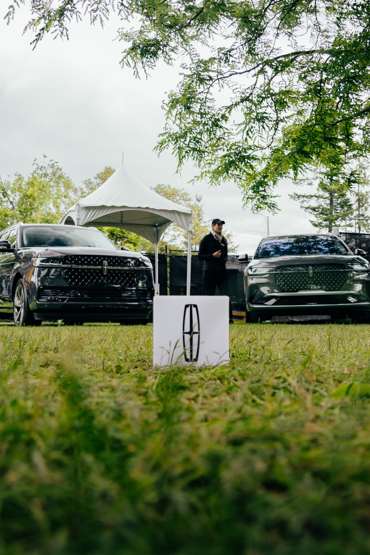 Two Lincoln SUVs parked on a lawn at an outdoor brand event